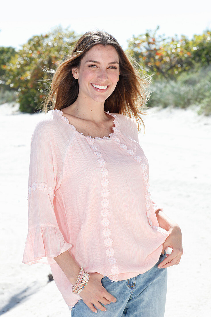 A young woman wearing a pastel pink tunic and jeans