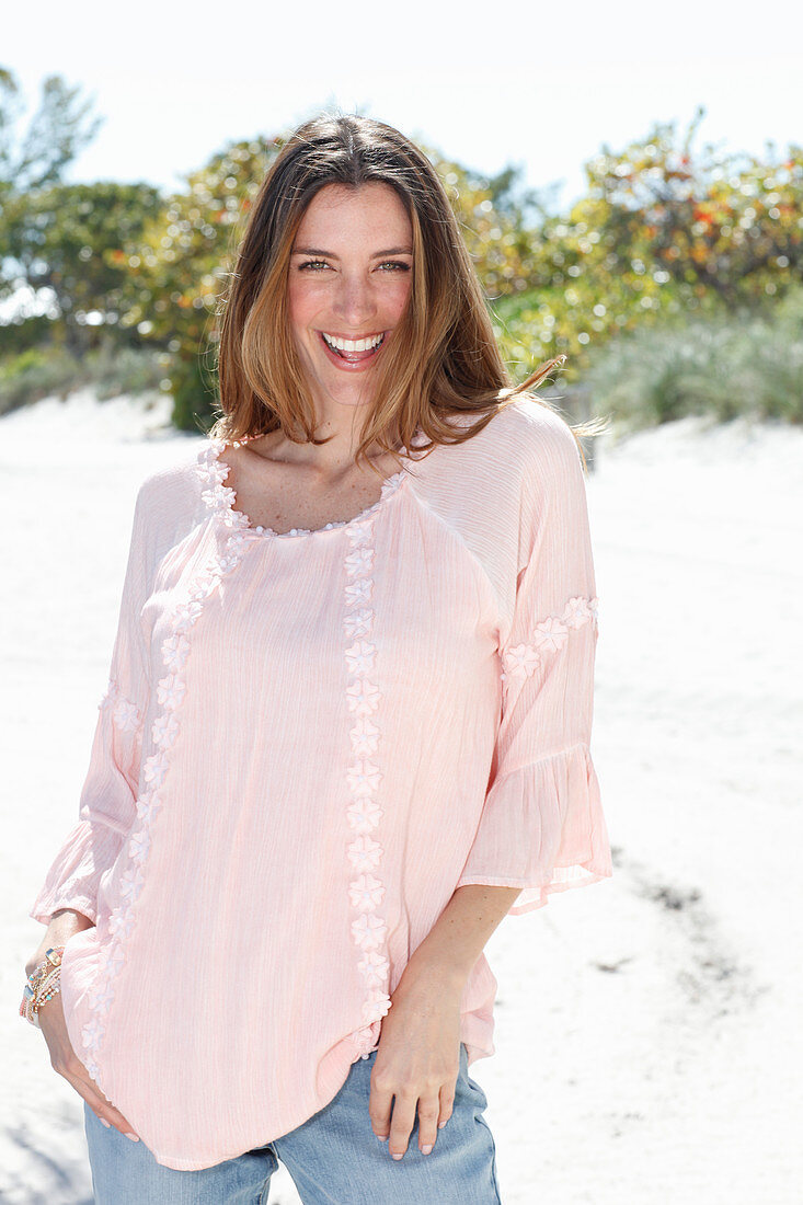 A young woman wearing a pastel pink tunic and jeans