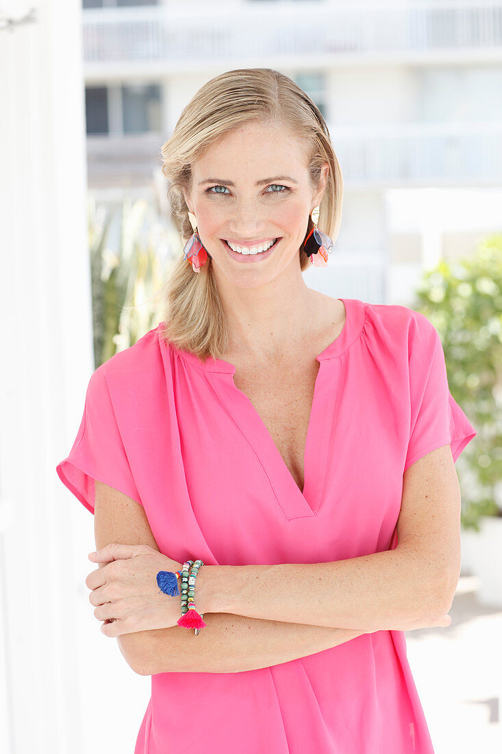 A blonde woman wearing a pink blouse