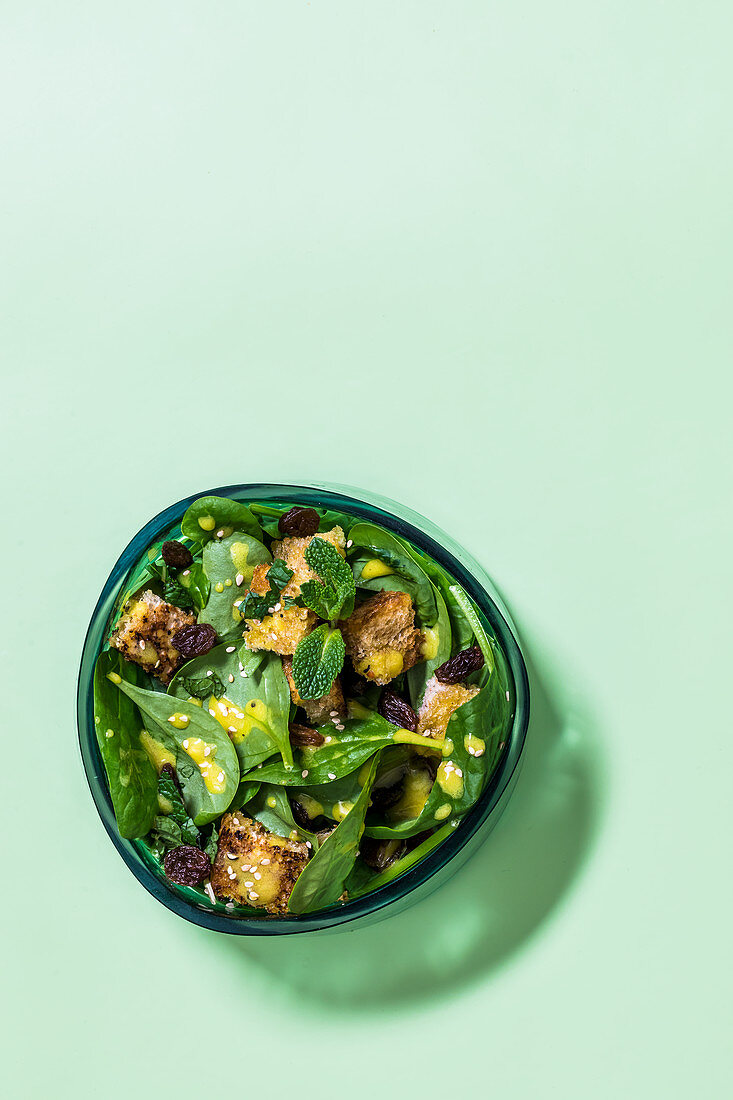 Oriental spinach salad with croutons, raisins and mint