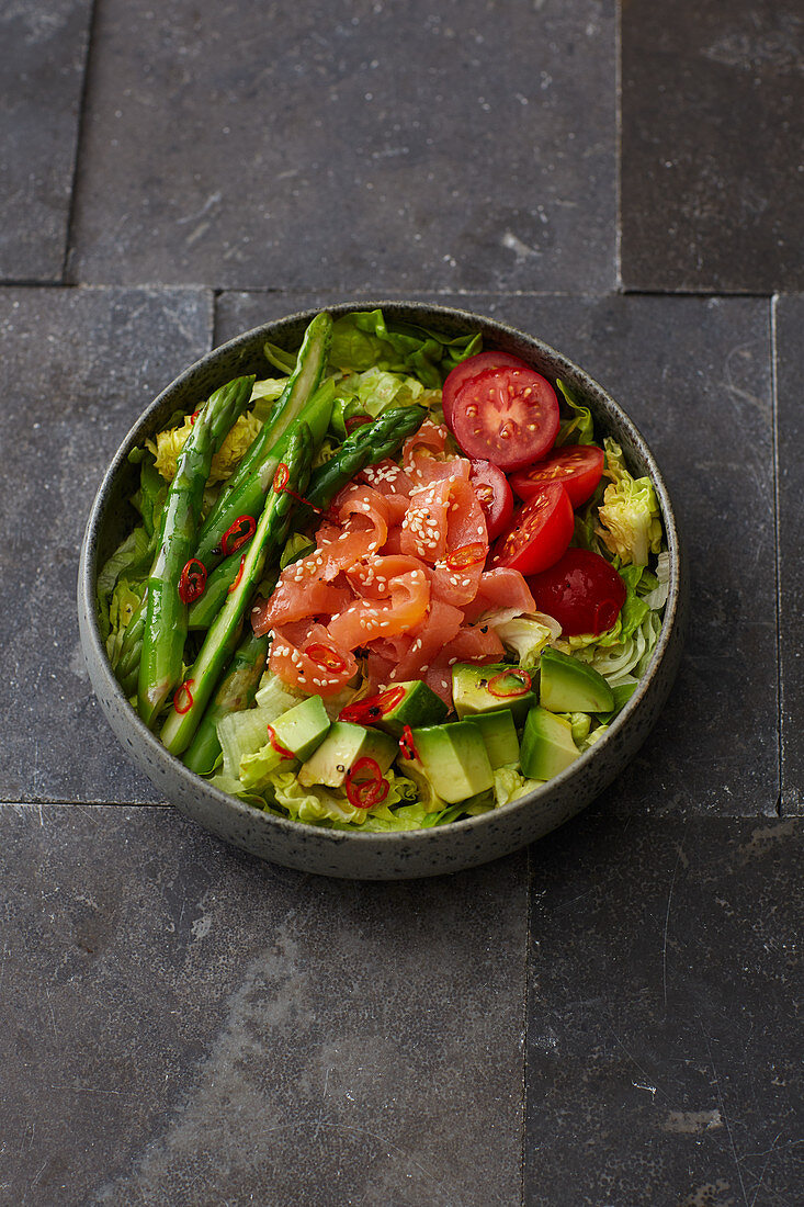 A salad bowl with salmon and green asparagus