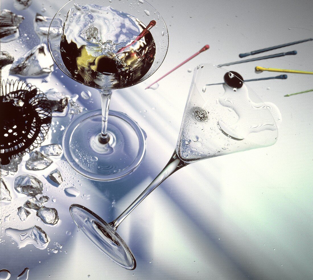 Ein Glas Martini mit Olive & ein umgekipptes Martiniglas