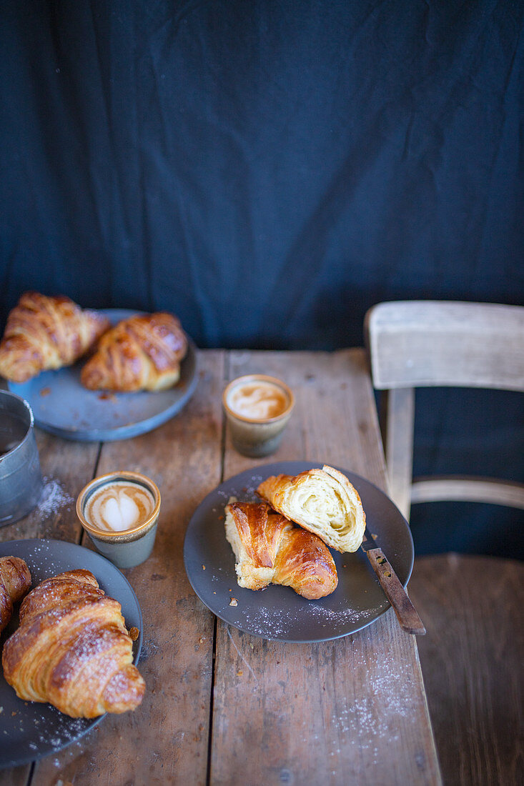 Croissants mit Cappuccino auf rustikalem Holztisch