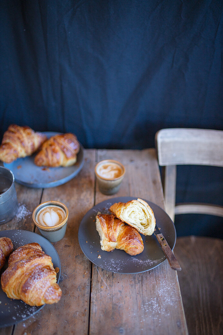 Croissants with cappuccinos on a rustic wooden table