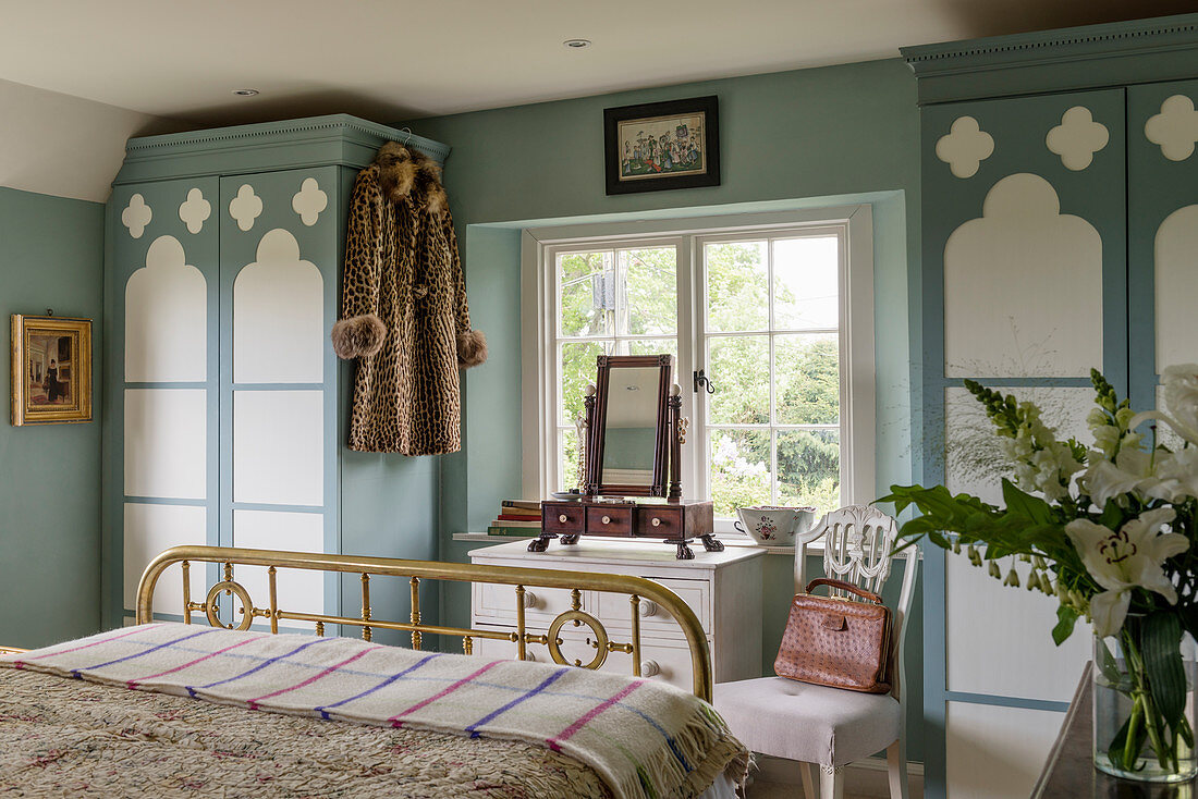 Blue-and-white bedroom with fitted wardrobes and brass bed
