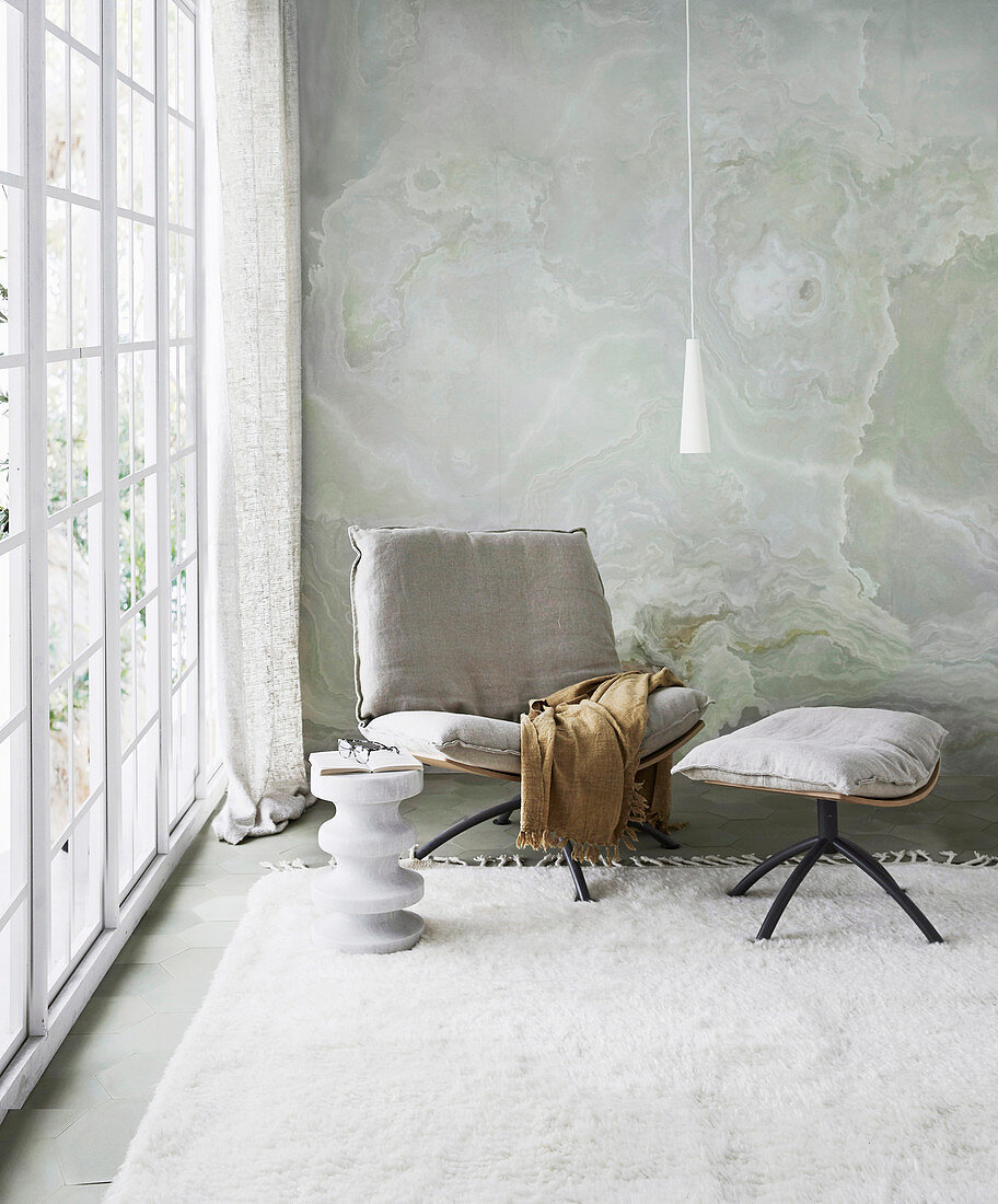 Chair with linen upholstery and footrest in sitting area by the window