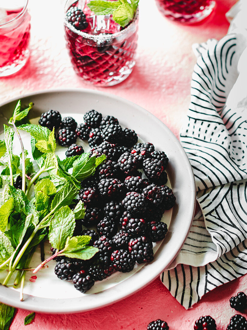 Blackberries and mint leaves on the white plate