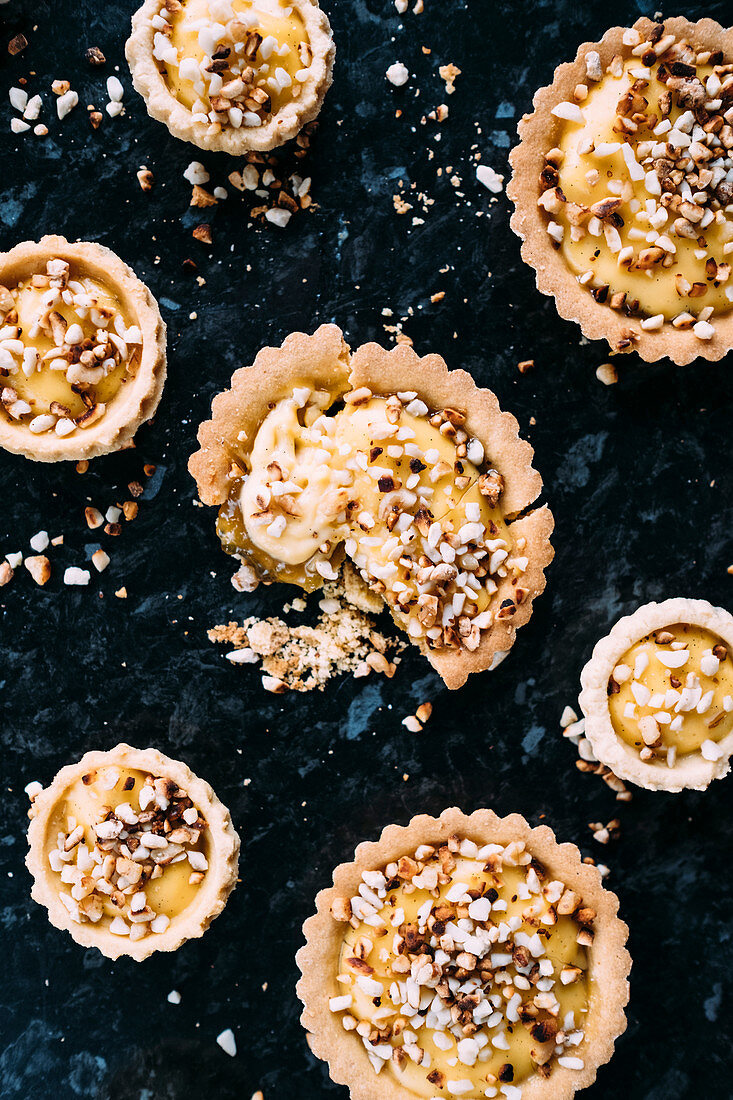 Shortcrust pastry custard tarts with a rhubarb and ginger conserve filling and toasted chopped nut topping