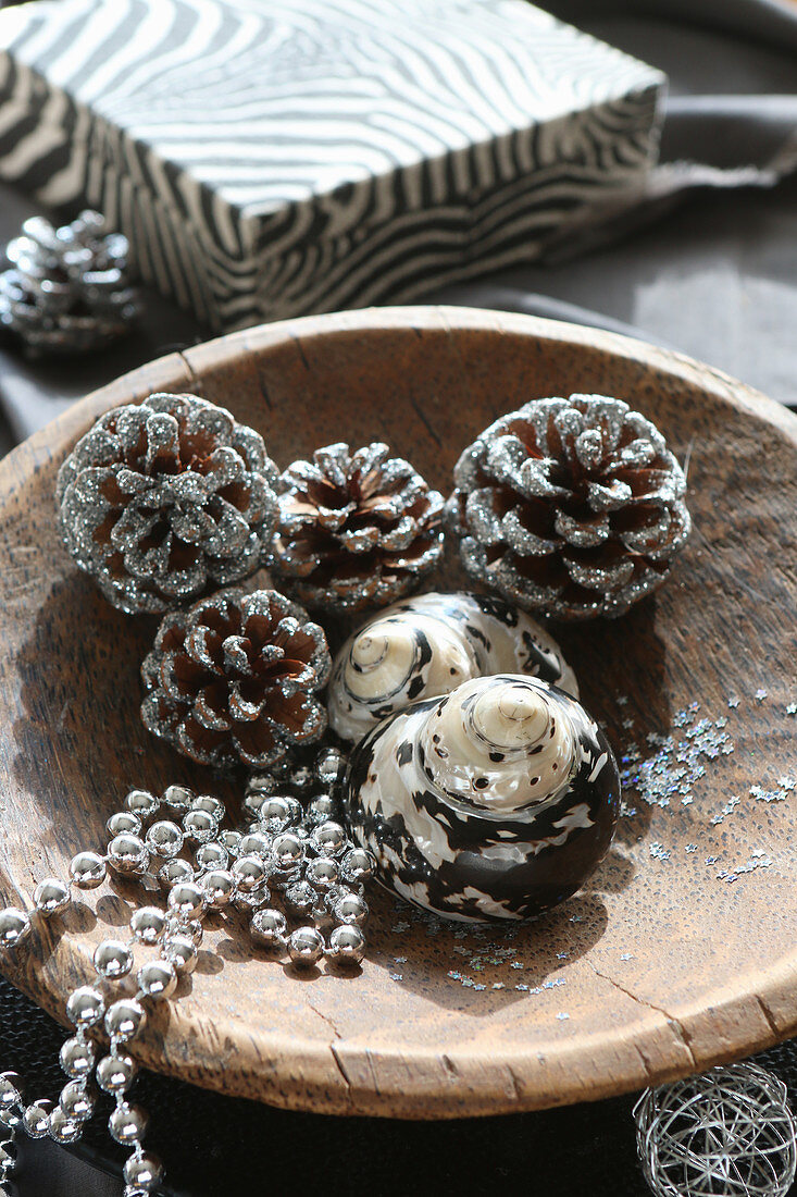 Christmas decorations in natural shades in wooden bowl in front of zebra-patterned box