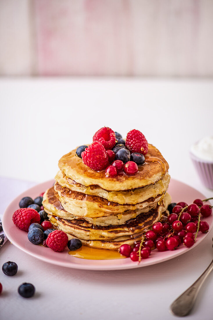 Ein Stapel Pancakes mit Honig und Beeren