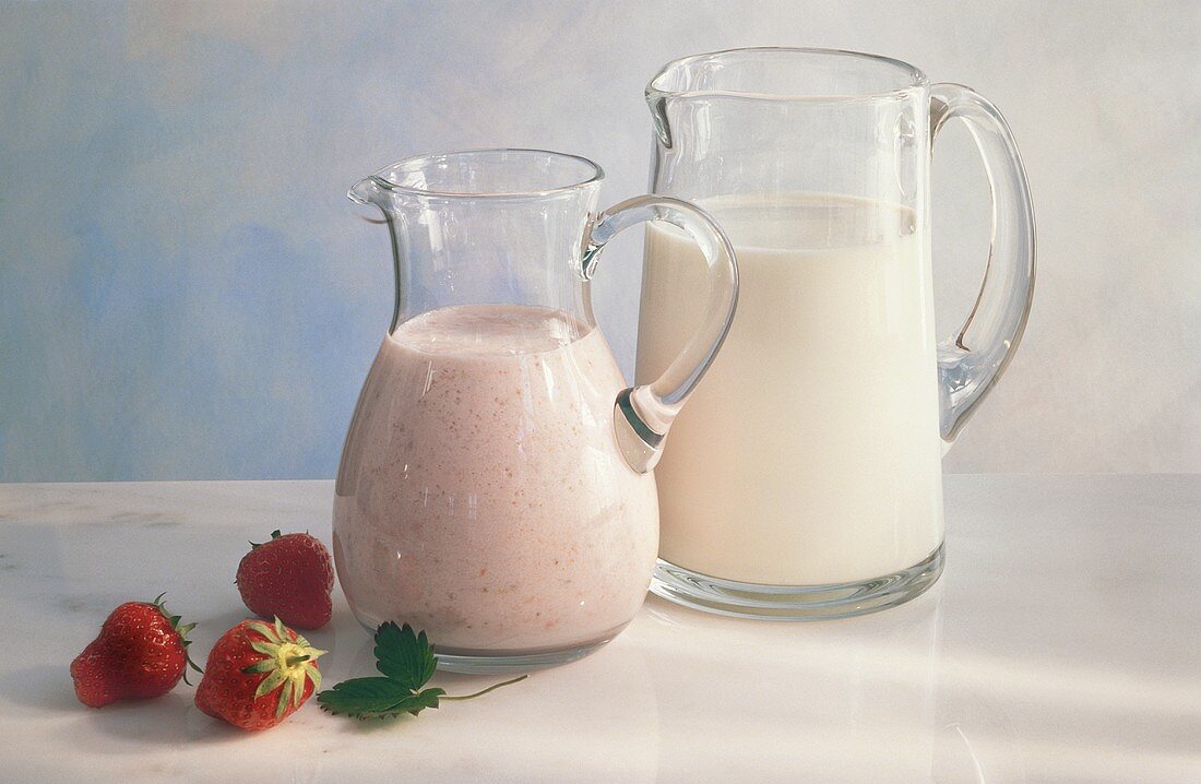 Zwei Glaskrüge mit Milch & Erdbeermilch