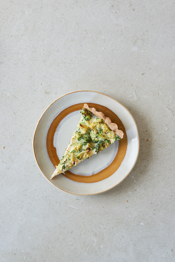 A slice of broccoli quiche with walnuts on a plate