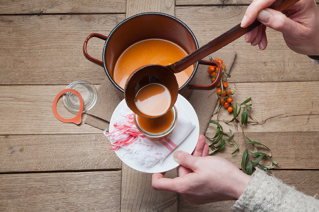 Pouring hot buckthorn jam into a mason jar