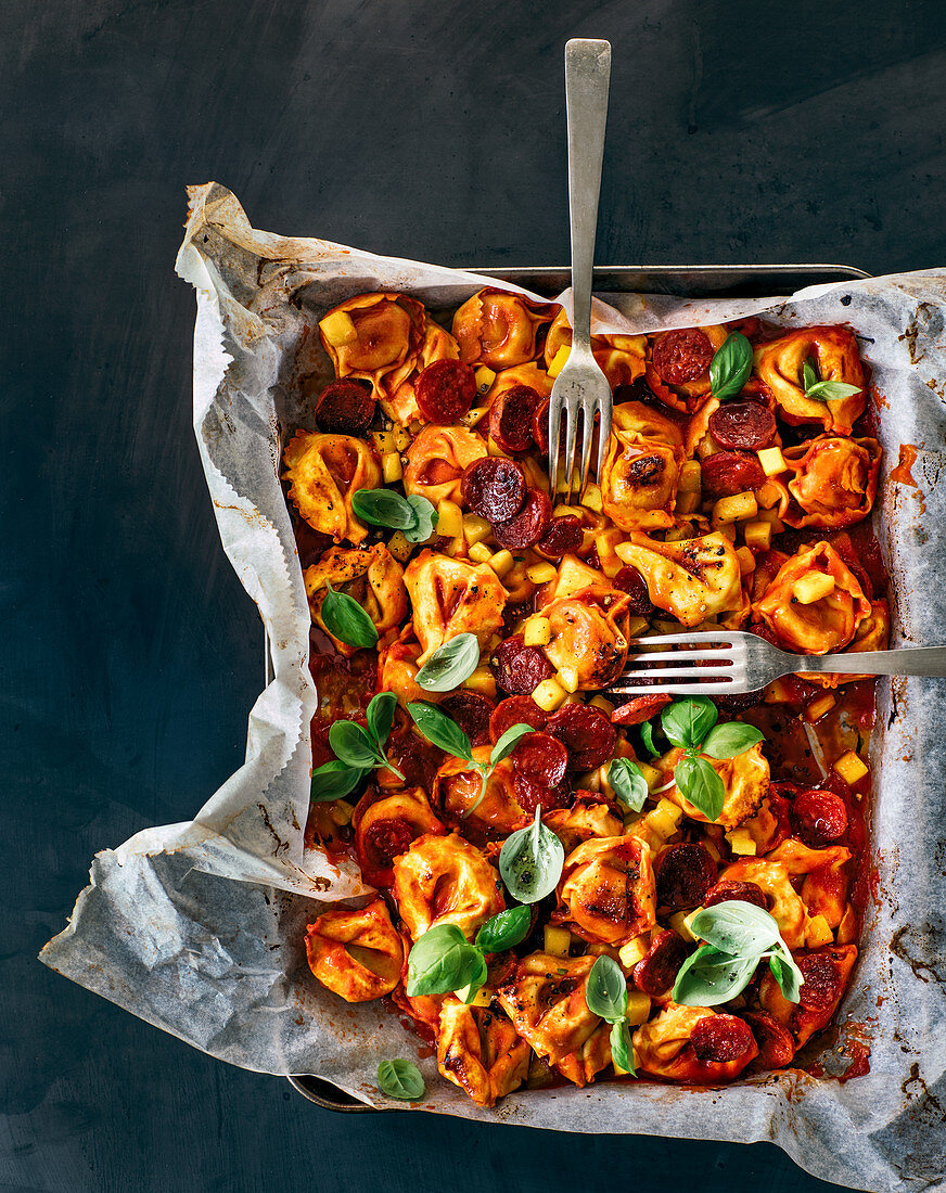 Tortelloni with chorizo, and mango-tomato sauce on an oven tray