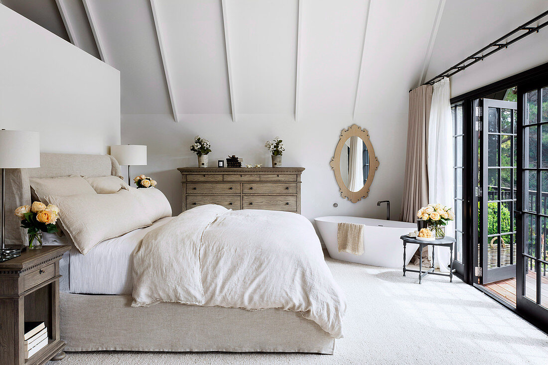 Bedroom with freestanding bathtub next to patio door