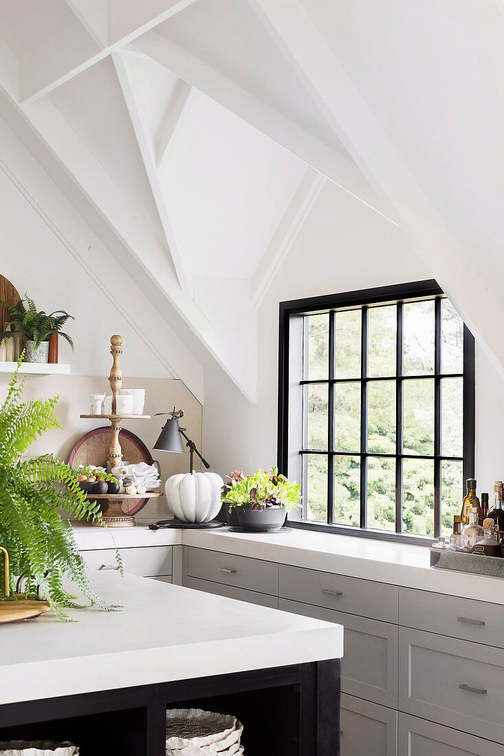 Kitchen under white gable roof with black transom window and kitchen island
