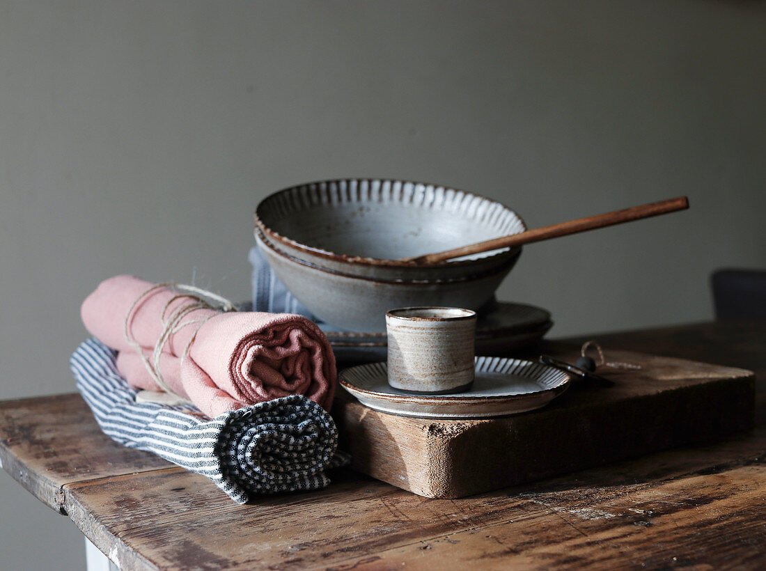 Bakery shapes near dishcloths, paddle, plates and bowls on wooden table on grey background