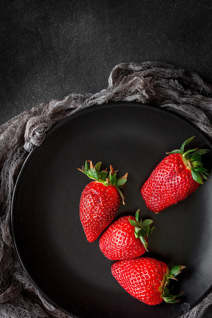 Frische Erdbeeren auf schwarzem Teller