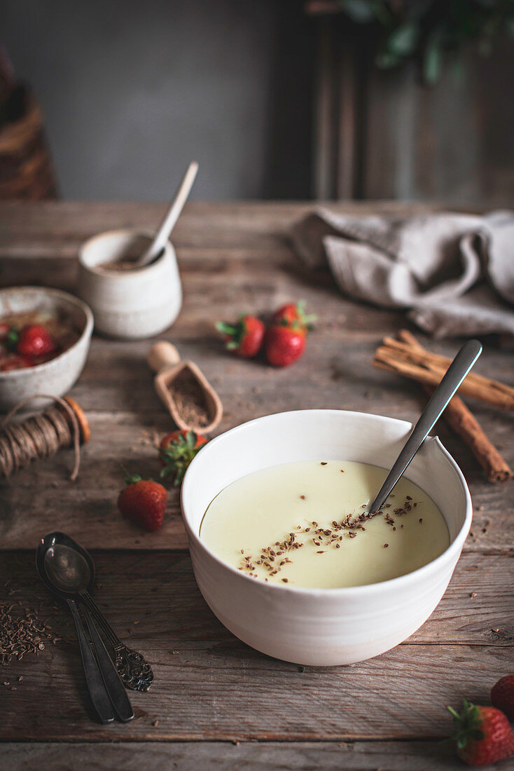 Bowl with sweet porridge garnished with spices and strawberry