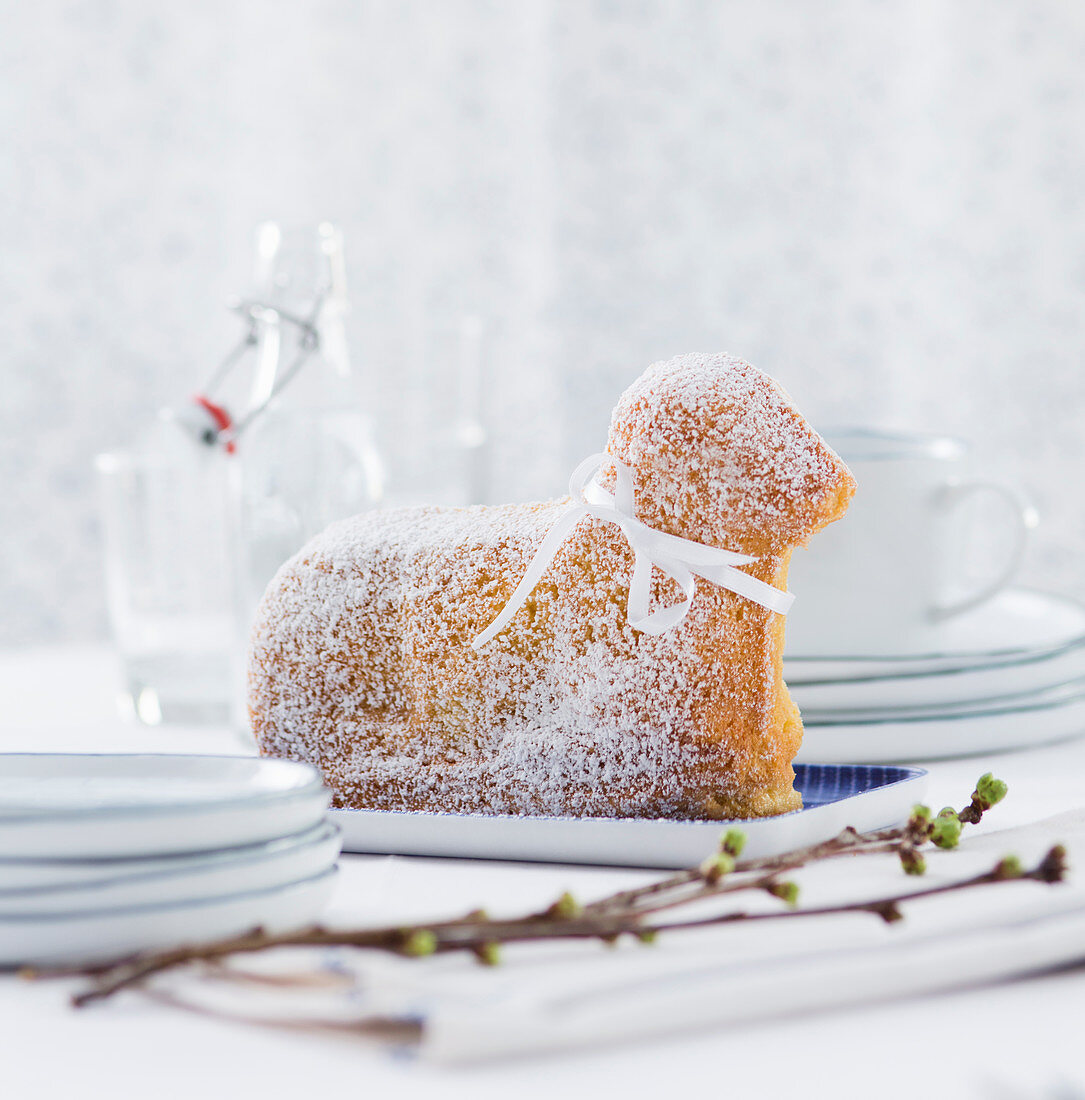 Gebackenes Osterlamm mit Puderzucker und Schleifchen auf Tisch