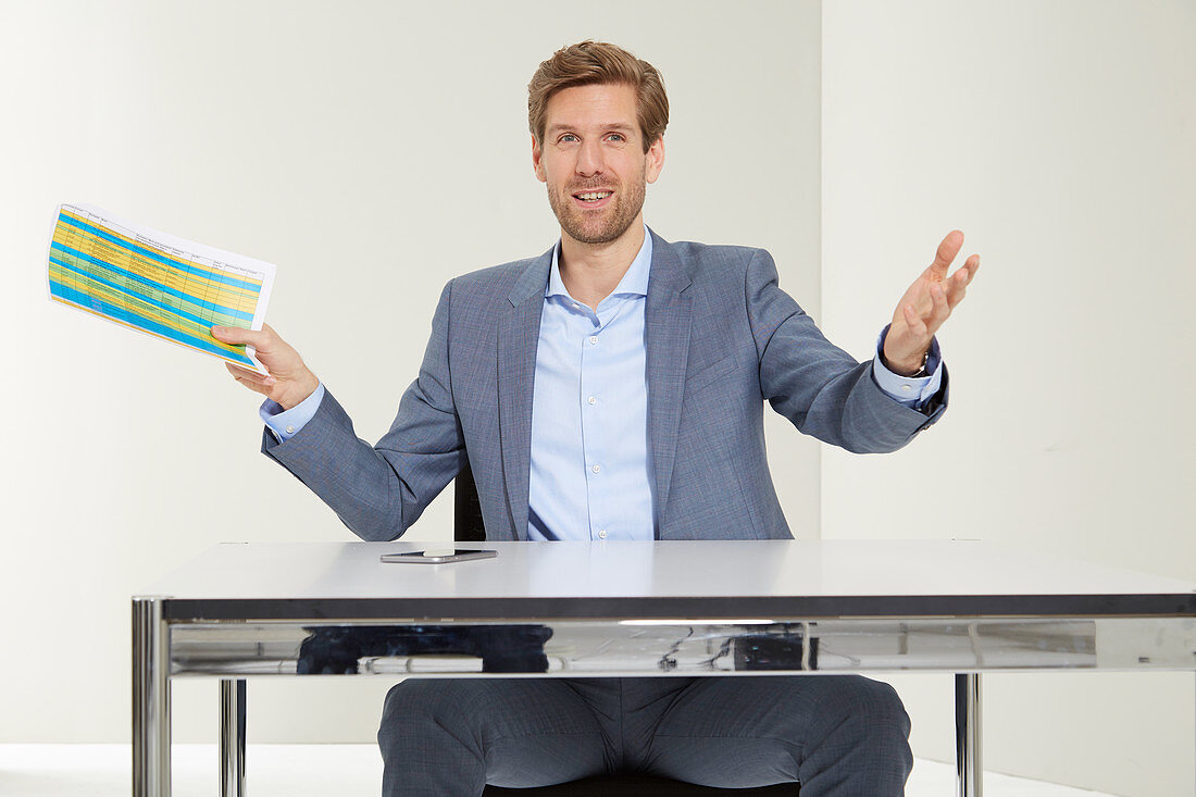 A business man at a desk making an inviting gesture