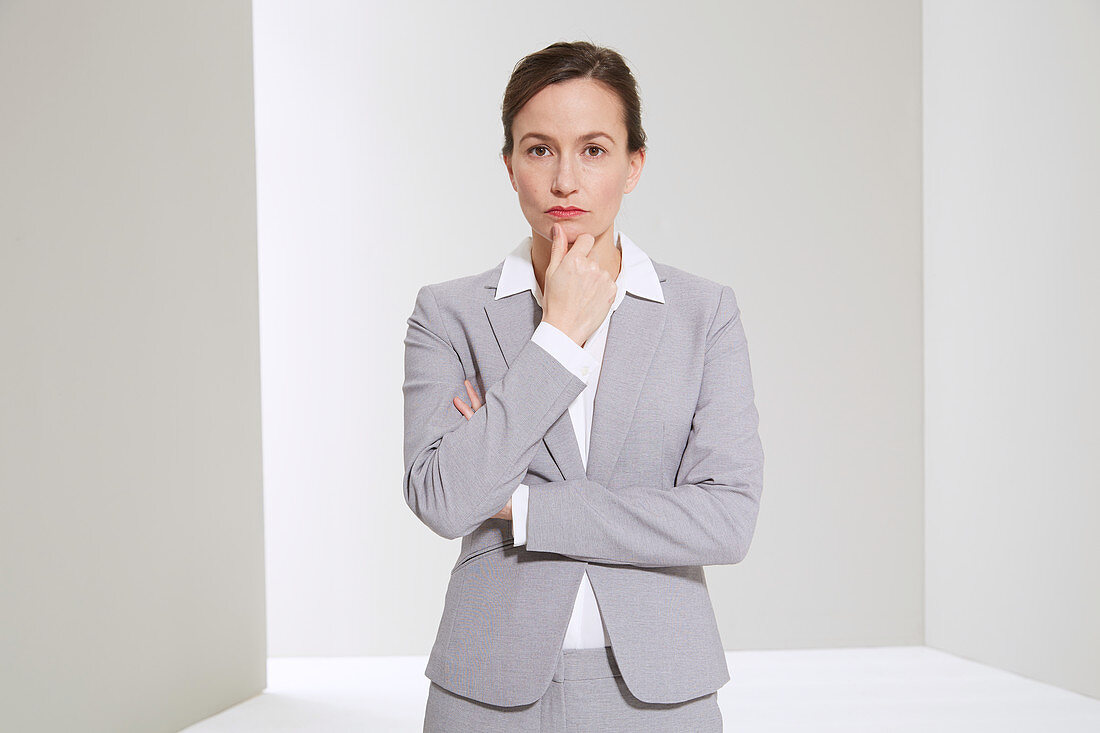 A business woman holding her thumb to her chin