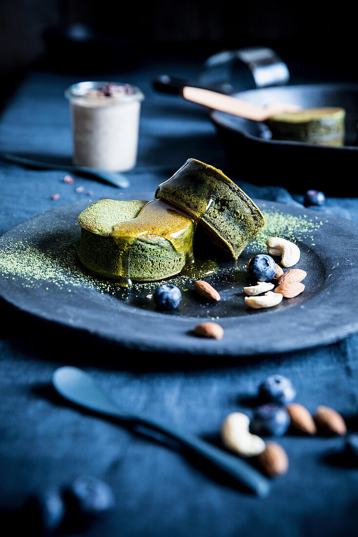 Matcha pancakes with honey, nuts, almonds and blueberries on a plate