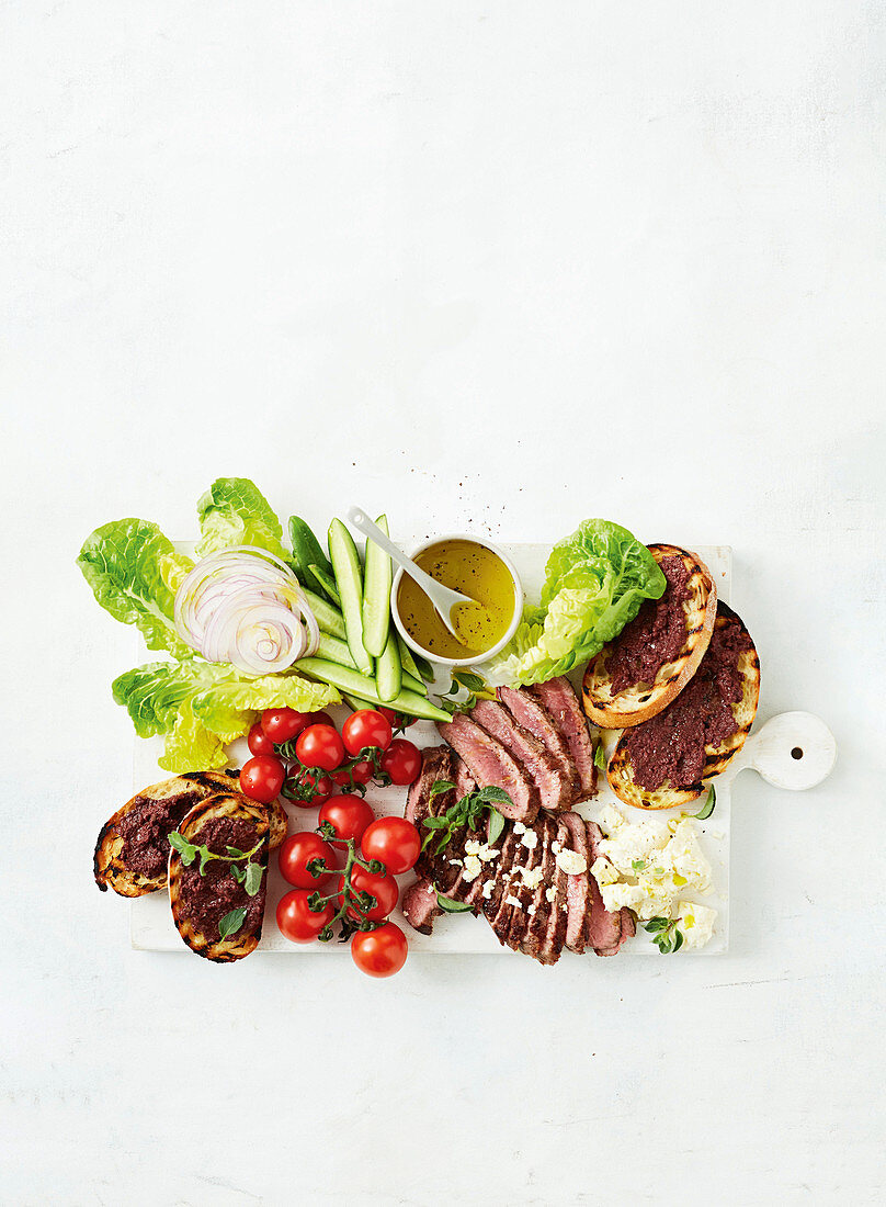 Griechische Salatplatte mit Lamm, Blattsalat, Gemüse und Röstbrot