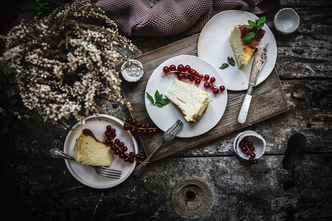 Drei Stücke Käsekuchen auf Tellern mit roten Johannisbeeren