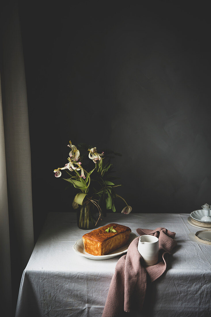Zitronenkuchen auf rustikalem Tisch mit Blumen