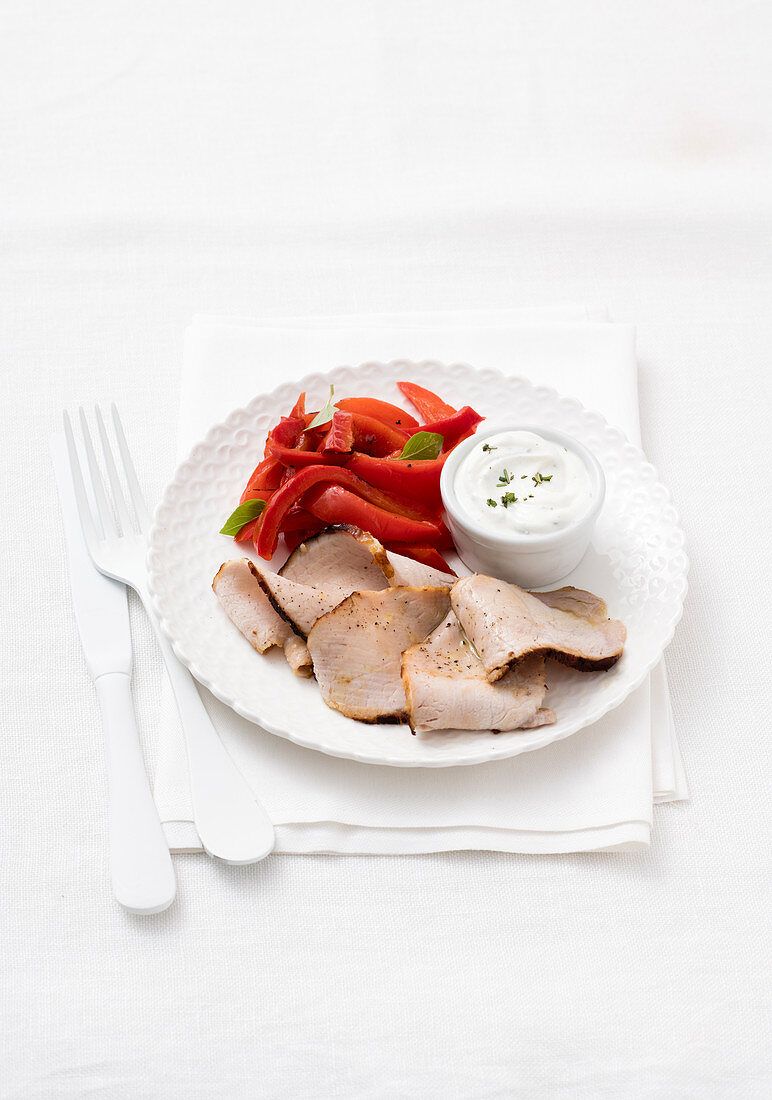 Kalter Schweinebraten mit Joghurt-Kräuter-Sauce und Paprikastreifen