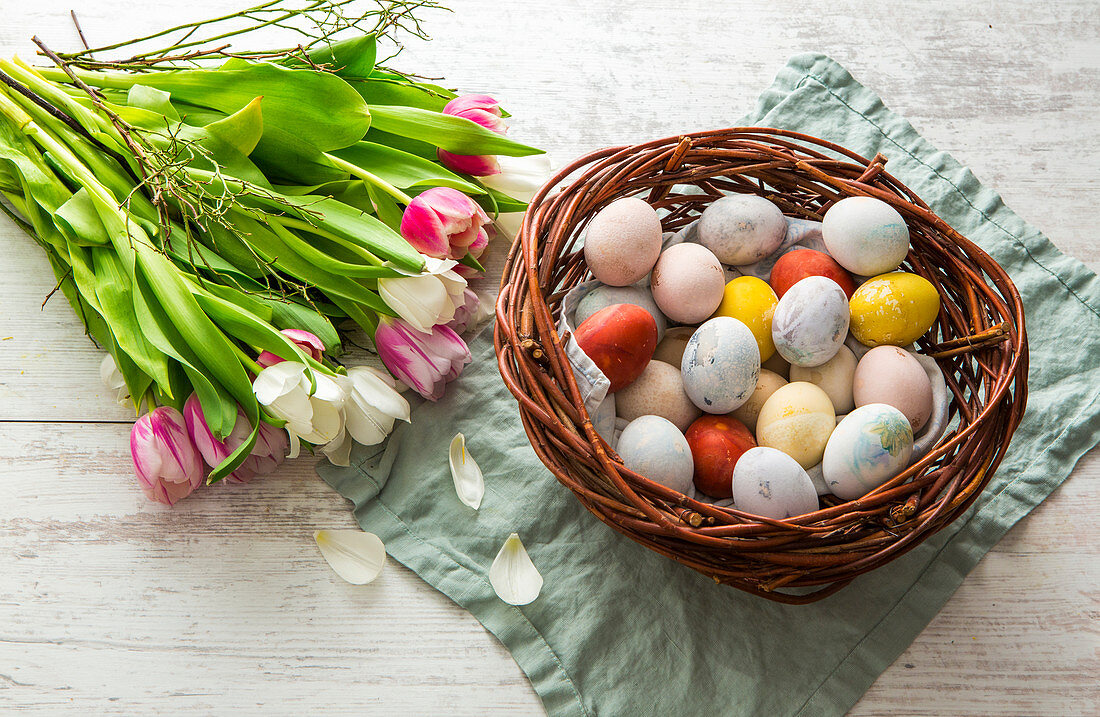 An Easter nest filled with colourful Easter eggs and a bunch of tulips