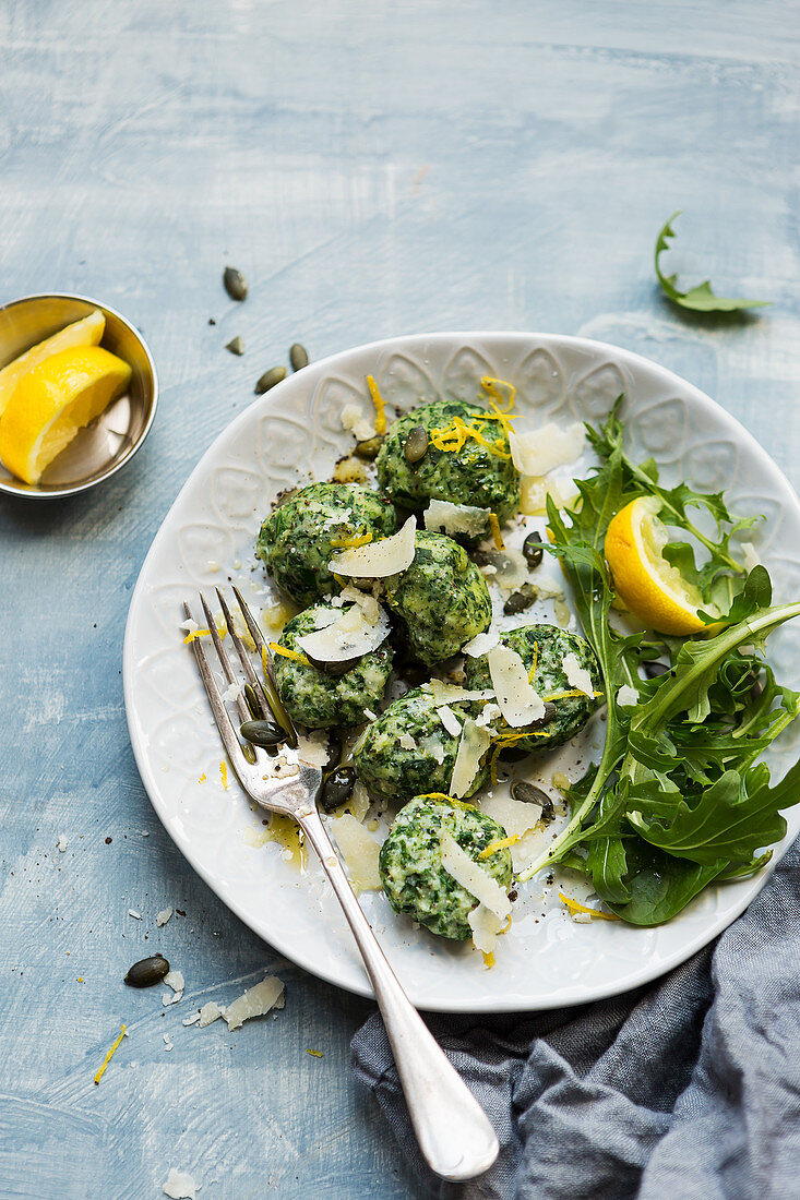 Spinach gnocchi homemade recipe served with mixed leaf salad, parmesan, pumpkin seeds and lemon zest