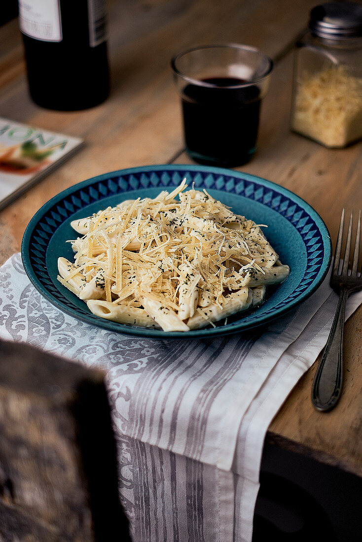 Penne mit Käse auf Holztisch mit Wein