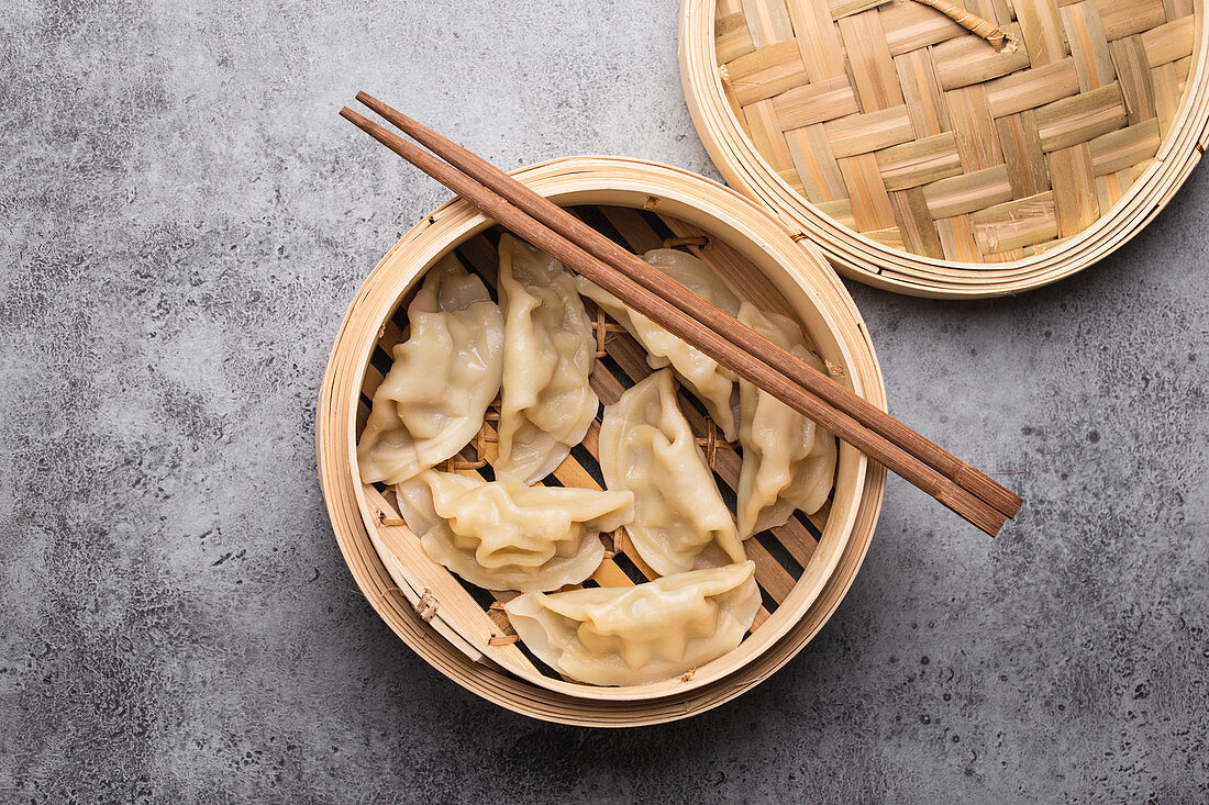 Traditional Chinese dumplings in bamboo steamer with chopsticks