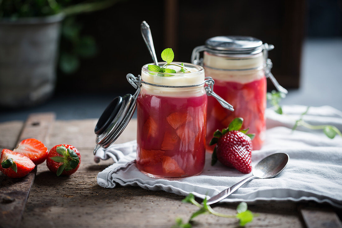 Zwei Gläser vegane Erdbeergrütze mit frischen Früchten und Vanillesauce