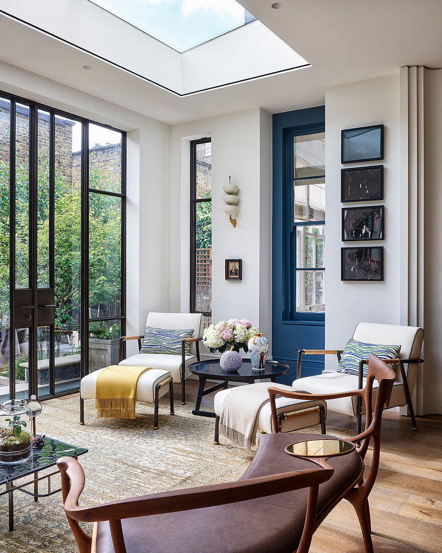 White armchairs with footstools below skylight next to terrace doors