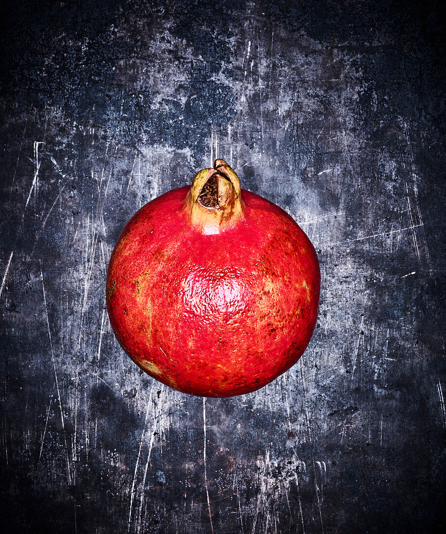 A pomegranate on a grey metal surface