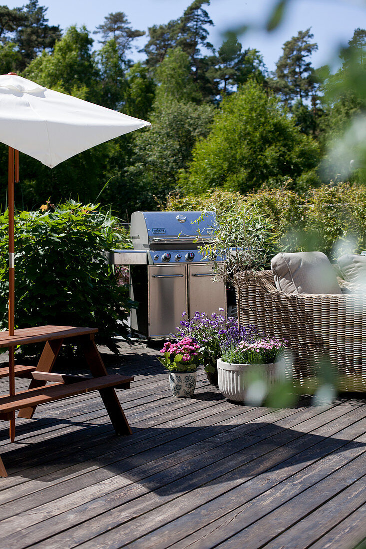 Barbecue, picnic table and wicker sofa on summery terrace