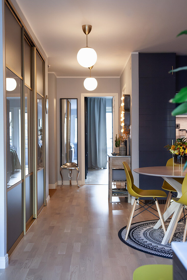 Fitted cupboards with sliding doors in hallway opening onto open-plan kitchen and dining area