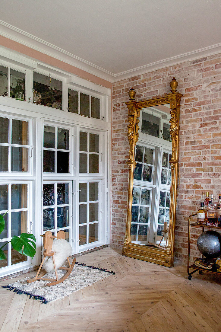 Antique gilt-framed mirror against brick wall