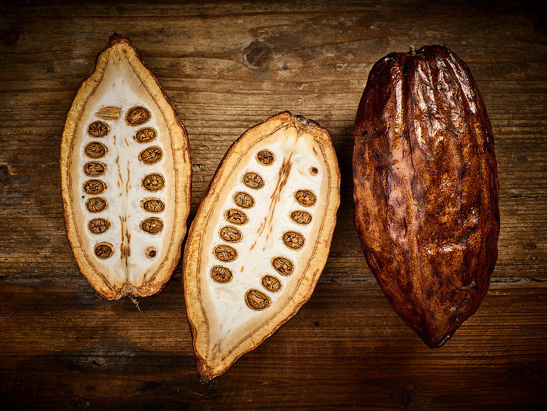Kakaoschoten, ganz und halbiert auf Holzuntergrund