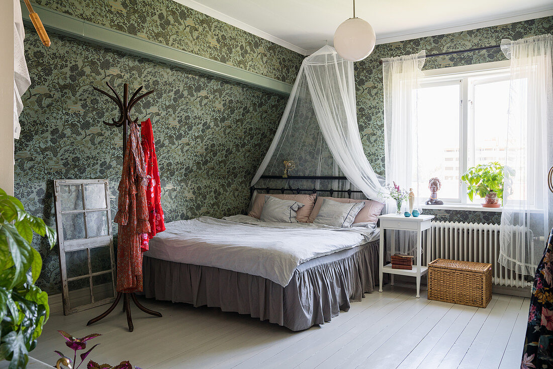 Bed with valance and canopy in bedroom with vintage-style wallpaper