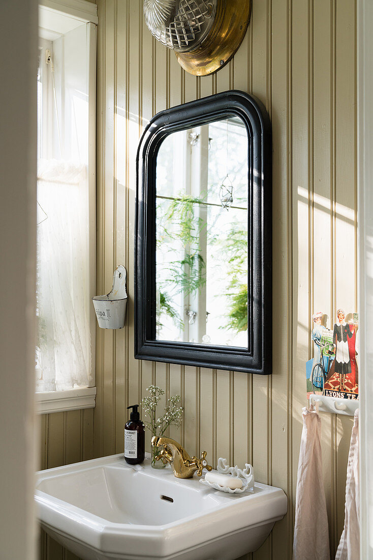 Mirror on board wall above sink in rustic bathroom