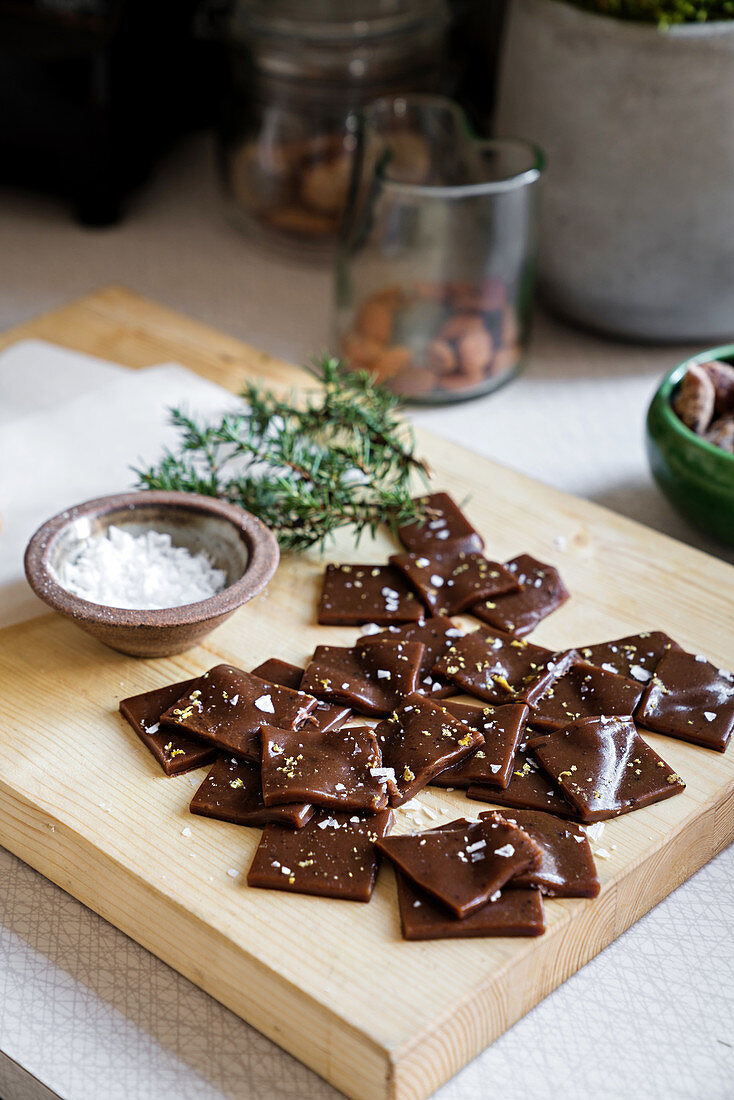 Chocolate shards with salt and rosemary on wooden board