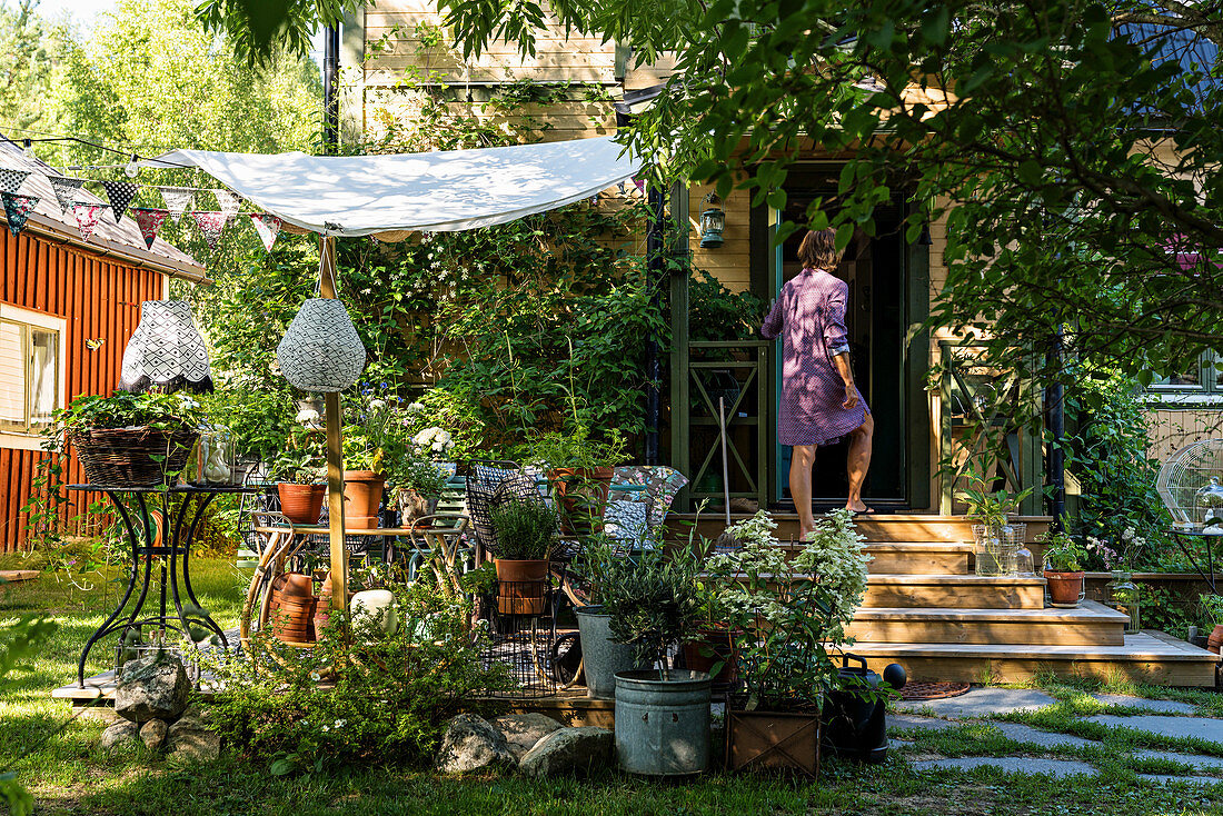 Idyllischer Terrassenplatz unterm Sonnensegel im sommerlichen Garten