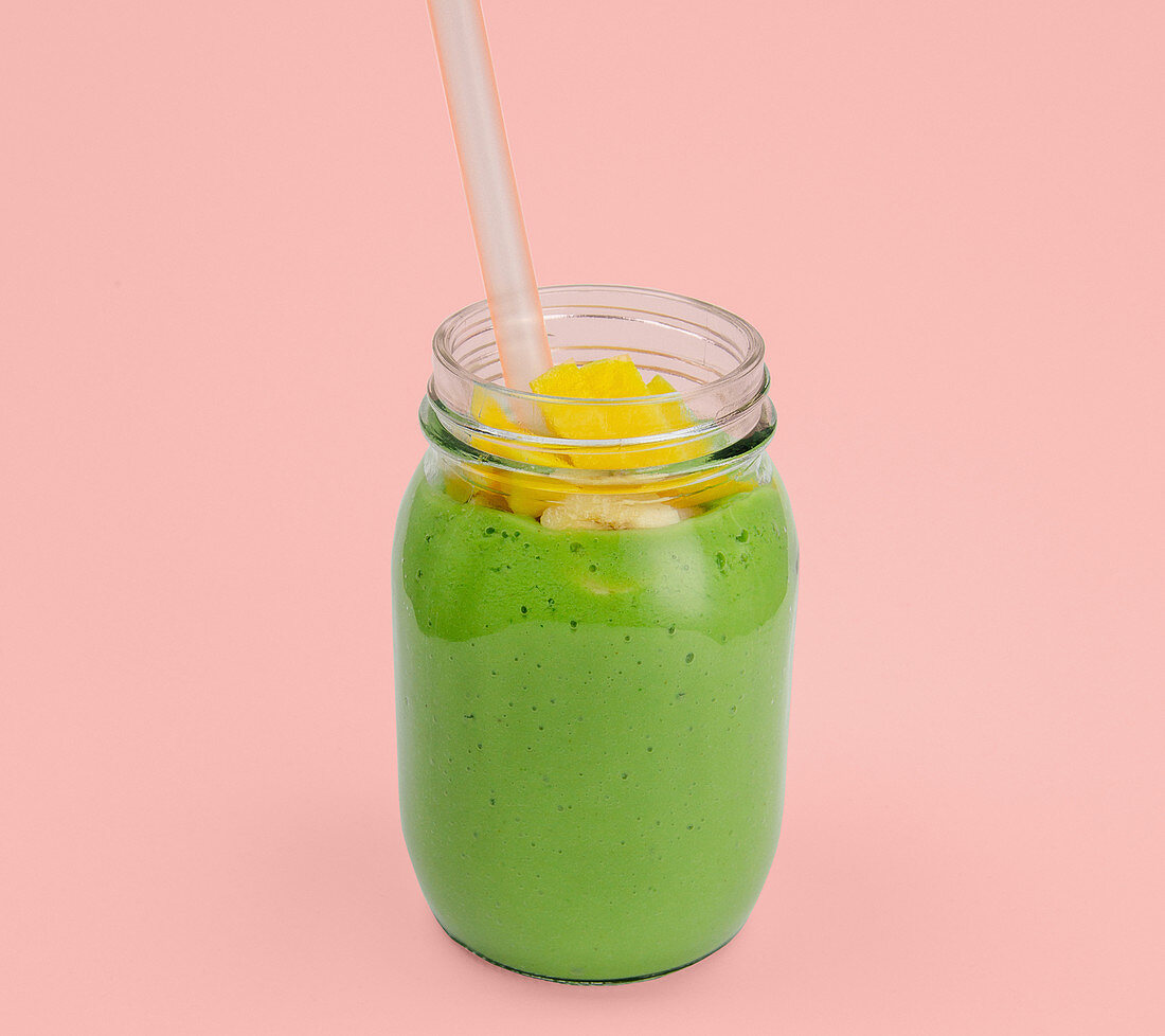 A smoothie made from rocket, mango, banana and milk in a screw-top jar