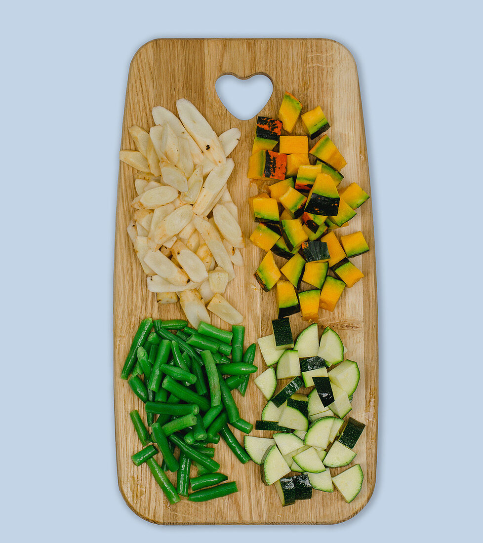 Chopped vegetables (black salsify, pumpkin, courgette, green beans) on a wooden board