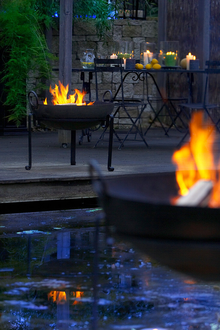 Fire bowls around pond in twilight garden