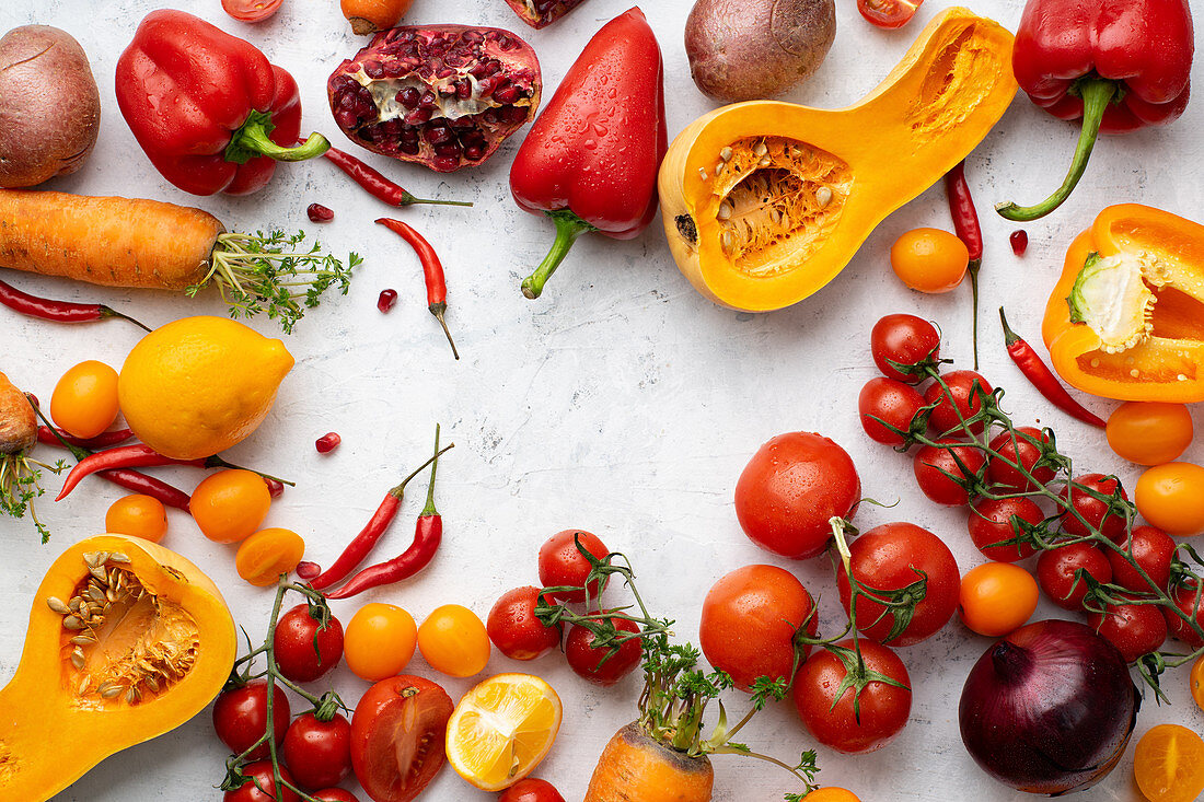 Flatlay with colorful vegetables arranged on white background (Tomatoes, squash and peppers)